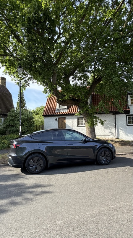 Side profile of the Model Y by a country cottage
