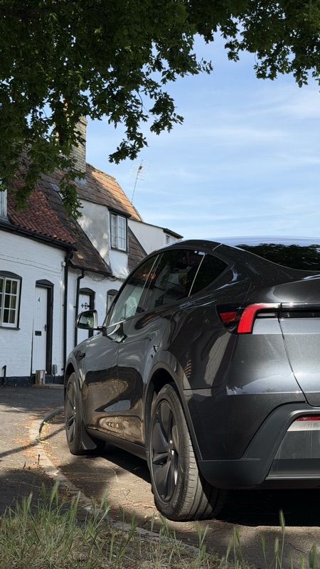 Rear view of the Model Y RWD by a cottage