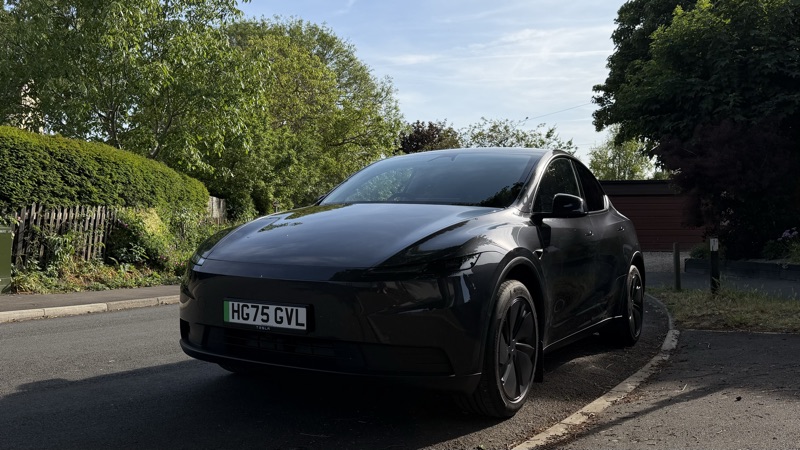 Side view of the Model Y, road, hedge in background