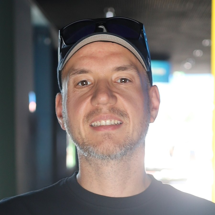 Tom Stacey, grinning, sunglasses pushed up on a cap